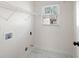 Bright laundry room featuring a window, white walls, and marble-look tile floors at 2038 Cresthaven Walk, Woodstock, GA 30189