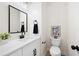 Elegant powder room featuring white vanity with black fixtures and a decorative mirror and framed artwork at 2038 Cresthaven Walk, Woodstock, GA 30189