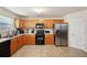 Functional kitchen featuring wood cabinets, black appliances, stainless steel refrigerator, and tile flooring at 3308 Hunting Creek Pass, Douglasville, GA 30135