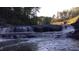 Scenic view of a natural waterfall cascading over rocks, surrounded by lush trees on a sunny day at 3308 Hunting Creek Pass, Douglasville, GA 30135