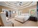 Luxurious bedroom with tray ceilings, a plush bed, and a view into a game room at 2805 Cambria Ct, Cumming, GA 30041