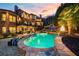 Backyard view featuring a large pool, tiered patios, outdoor fireplace, and manicured landscaping at twilight at 2805 Cambria Ct, Cumming, GA 30041