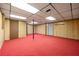 Large basement space with red carpet, wood paneling, and drop ceiling perfect for finishing at 7281 Fernwood Dr, Riverdale, GA 30296
