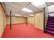 Spacious basement with red carpet, wood paneling, and a drop ceiling, ready to be finished at 7281 Fernwood Dr, Riverdale, GA 30296