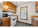 A view of the kitchen, featuring wood cabinets, oven, black and white patterned flooring, and a window at 7281 Fernwood Dr, Riverdale, GA 30296