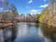 Serene view of a pond surrounded by trees, reflecting the sky and creating a peaceful natural scene at H-5422 Hill Sw Rd, Powder Springs, GA 30127