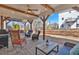 Covered outdoor patio featuring stone pavers, wood beams, ceiling fan, and a cozy seating area at 203 Roseman Way, Woodstock, GA 30188