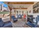 Cozy covered patio with stone pavers, wood beams, ceiling fan, outdoor seating, and grill at 203 Roseman Way, Woodstock, GA 30188