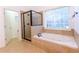 Bright bathroom featuring a tiled shower, a soaking tub and a large window at 2474 Starfire Ln, Loganville, GA 30052