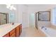 Bathroom showcasing double vanities, a separate shower, and a soaking tub beneath a bright window at 2474 Starfire Ln, Loganville, GA 30052
