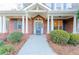 Inviting front porch with brick facade, white columns, and beautifully landscaped bushes at 2474 Starfire Ln, Loganville, GA 30052