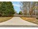 Long concrete driveway leading up to a well-maintained property with mature trees and a fenced backyard at 504 Leguin Mill Rd, Locust Grove, GA 30248