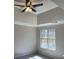 This bedroom has a window, fresh gray paint, carpet and a tray ceiling with a ceiling fan at 6910 Stone Breeze Dr, Stone Mountain, GA 30087