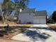 Two-story home featuring a gray siding facade with a two-car garage and driveway at 6910 Stone Breeze Dr, Stone Mountain, GA 30087