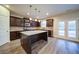 A kitchen with dark wood cabinets, granite countertops, a central island with pendant lighting, and access to the backyard at 4280 Hunters Walk Way, Cumming, GA 30028