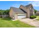 View of home's side with a two-car garage and manicured green lawn on a sunny day at 2586 Abbotts Glen Dr, Acworth, GA 30101