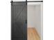 Walk-in closet featuring wood floors and a modern black barn door at 3567 New Hope Rd, Dacula, GA 30019