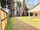 Well-maintained backyard featuring a wooden fence, mature trees, and a covered patio area at 125 Whistle Way, Locust Grove, GA 30248