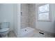 Bathroom featuring a tiled shower with a built-in niche, a modern toilet, and a window at 279 Laura Cir, Bowdon, GA 30108