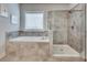 Spa-like bathroom featuring a separate shower, soaking tub, and neutral tile at 5242 Park Vale Dr, Sugar Hill, GA 30518