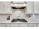 Close-up of kitchen stove and tile backsplash with white cabinets and granite countertops, stylish and functional at 5242 Park Vale Dr, Sugar Hill, GA 30518