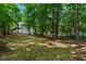 Large backyard with fresh straw and a white home surrounded by lush green trees at 74 Rotunda Ct, Dallas, GA 30157