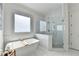 Bathroom with a soaking tub, large window, glass enclosed shower, and white tile at 2892 Darlington Run, Duluth, GA 30097