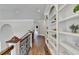 Hallway showcasing custom built-in bookshelves, hardwood flooring, and arched doorways at 2892 Darlington Run, Duluth, GA 30097