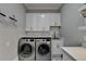 Modern laundry room with white cabinets, countertops, and stainless steel washer and dryer at 2892 Darlington Run, Duluth, GA 30097