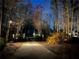 Long driveway with gate and brick pillars leading to a lovely home surrounded by lush greenery at night at 3045 Camp Branch Rd, Buford, GA 30519