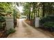 Long driveway with gate and brick pillars leading to a lovely home surrounded by lush greenery at 3045 Camp Branch Rd, Buford, GA 30519
