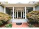 Inviting front porch with brick detail and stone tile, framed by elegant columns and lush greenery at 3045 Camp Branch Rd, Buford, GA 30519