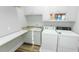 Well-lit laundry room with sink, folding table, and included washer and dryer at 3045 Camp Branch Rd, Buford, GA 30519