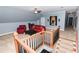 Upstairs living room featuring a red sofa, a large art piece, and a wooden railing overlooking the stairwell at 3045 Camp Branch Rd, Buford, GA 30519