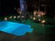 Nighttime view of a backyard pool with a hot tub, stone fireplace, and lounge seating at 3045 Camp Branch Rd, Buford, GA 30519