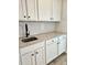 Kitchen view showcasing granite countertops, white cabinets with black hardware, and a stainless steel sink with a black faucet at 1685 Crumbley Rd, Mcdonough, GA 30252