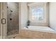 Bathroom features a glass walk-in shower and a soaking tub under a stained-glass window at 5640 Copper Creek Pass, Cumming, GA 30040