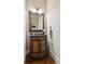 Charming powder room with decorative mirror, dark wood vanity, and hardwood floors at 5640 Copper Creek Pass, Cumming, GA 30040