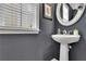 Elegant powder room featuring a pedestal sink, decorative mirror, and neutral wall color at 4165 Azurite St, Cumming, GA 30040