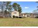 View of a split level home from a grassy backyard with privacy trees, a deck and a patio at 2696 Titon Way, Lawrenceville, GA 30044