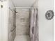 Shower with updated tile, shower head, and safety bars; accented by decorative shower curtain and wall decor at 2081 Beecher Sw Rd, Atlanta, GA 30311
