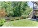 Inviting backyard features lush green lawn, landscaped garden beds, and a peaceful wooded backdrop at 607 Leland Pkwy, Cumming, GA 30041