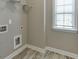 Functional laundry room features a window for natural light, wood-look flooring, and storage solutions at 607 Leland Pkwy, Cumming, GA 30041