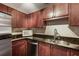 Well-lit kitchen with cherry cabinets, stainless steel appliances, granite countertops, and a double sink at 4254 River Green Nw Dr # 611, Atlanta, GA 30327