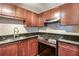 Well-lit kitchen with cherry cabinets, granite counters, stainless steel appliances, and a diamond backsplash at 4254 River Green Nw Dr # 611, Atlanta, GA 30327