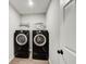 Modern laundry room with a white shelf and black, front-load washer and dryer at 4110 Ridgebrook Bnd, Cumming, GA 30028