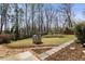 A charming backyard with a small playhouse, a stone walkway, and mature trees in the background at 1865 Butlers Ln, Decatur, GA 30033