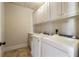 A laundry room with white washer and dryer and storage cabinets above at 1865 Butlers Ln, Decatur, GA 30033