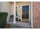 Inviting front porch featuring a black front door, brick accents, and decorative plants and chair at 2939 Greyhawk Ln, Cumming, GA 30040