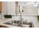 Close-up of a stainless steel kitchen sink with a modern faucet and view into the living area at 2939 Greyhawk Ln, Cumming, GA 30040